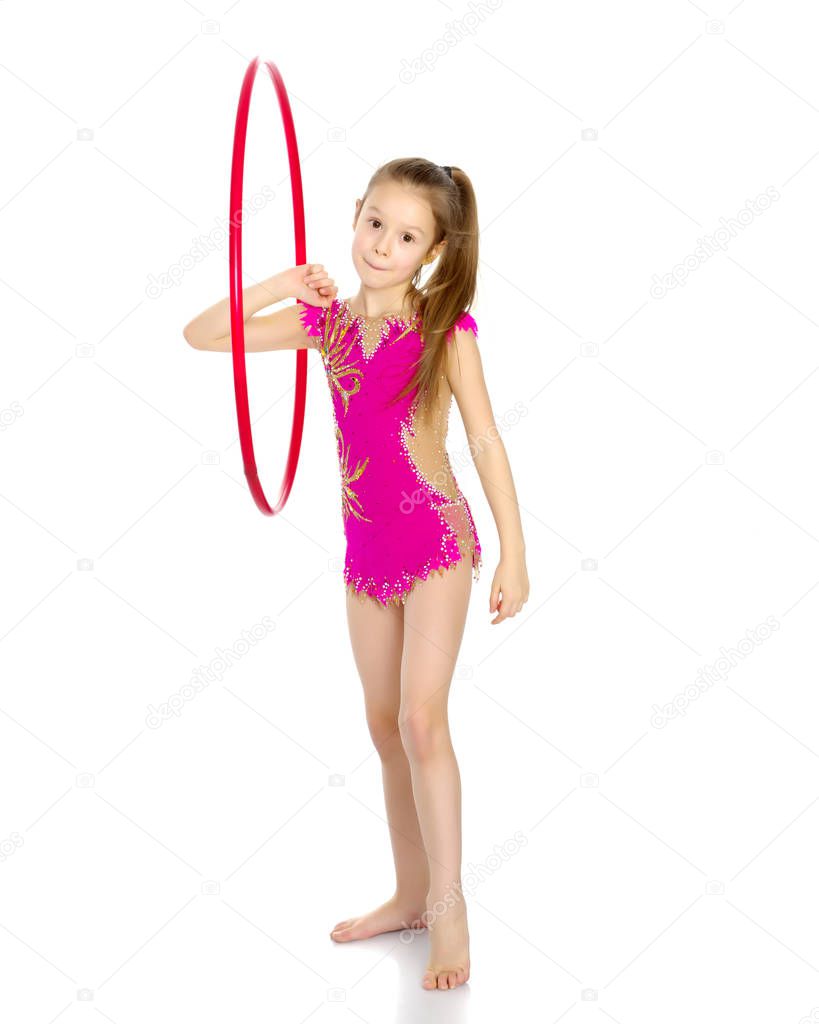 A girl gymnast performs an exercise with a hoop.