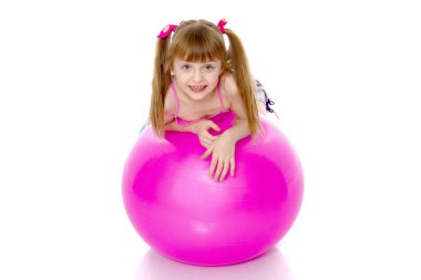 Küçük kız spor yapmak için büyük bir top üzerinde egzersiz yapıyor..