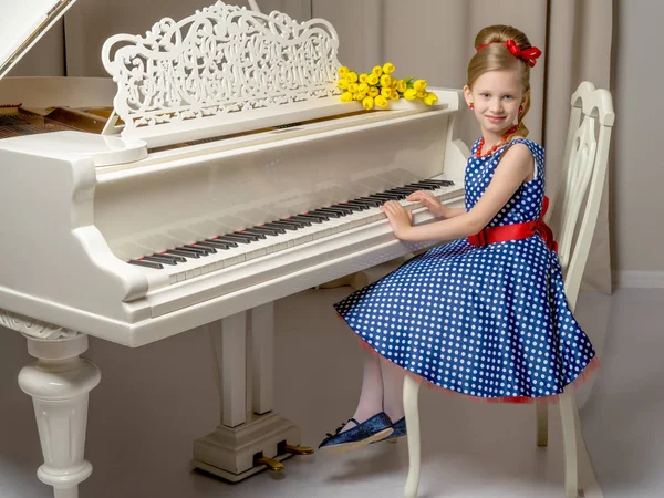 Meisje schoolmeisje in de buurt van de piano waarop ligt een boeket van bloem — Stockfoto