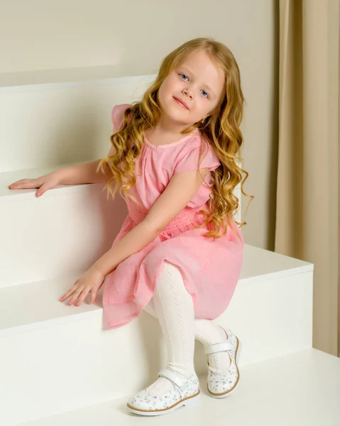 美丽的小女孩正坐在白色的楼梯上. — 图库照片
