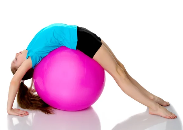 Liten flicka gör övningar på en stor boll för fitness. — Stockfoto