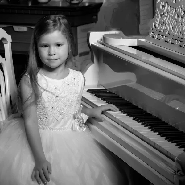 Klein meisje speelt piano bij kaarslicht. — Stockfoto