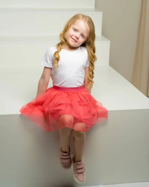 Güzel Elbiseli Sevimli Küçük Bir Kız Beyaz Bir Merdivende Oturuyor — Stok fotoğraf