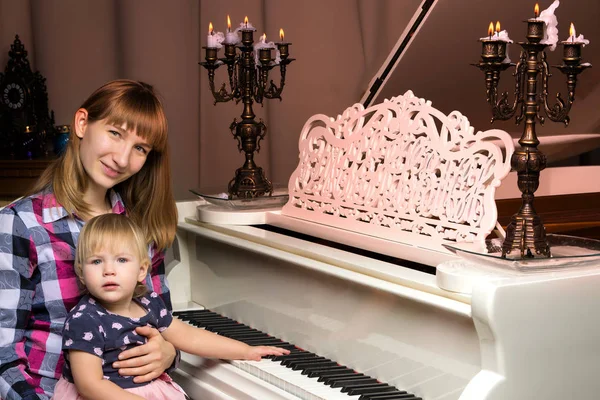 Bir çocuğun yanında beyaz piyano ile anne — Stok fotoğraf