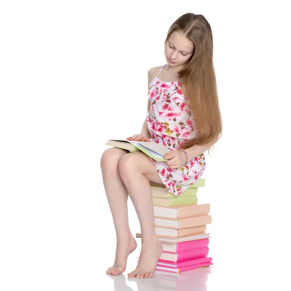 Schoolgirl sitting on a pile of books — Stock Photo, Image