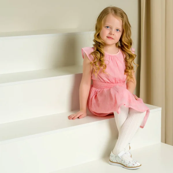 Güzel küçük kız beyaz merdivenlerde oturuyor.. — Stok fotoğraf