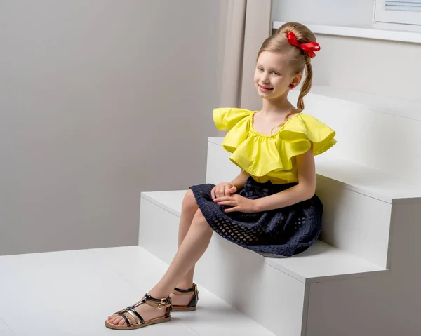 A little girl is standing on a white staircase. — Stock Photo, Image