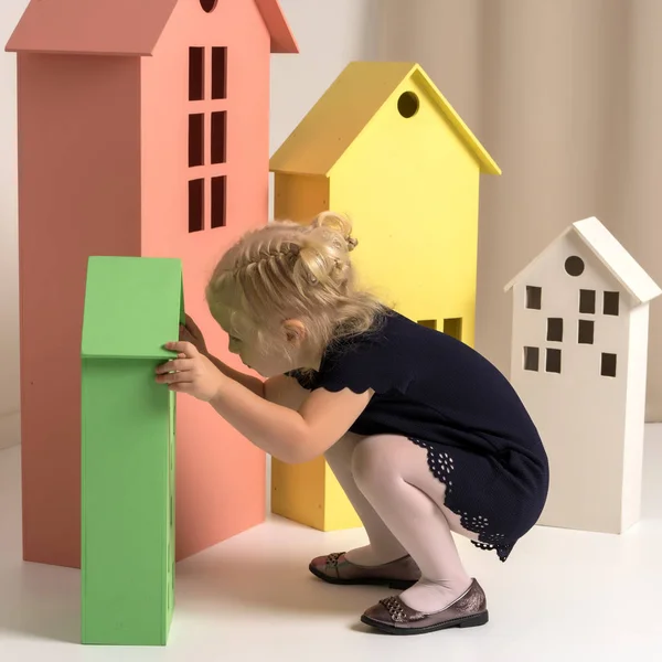 Kleines Mädchen spielt mit Holzhäusern. — Stockfoto