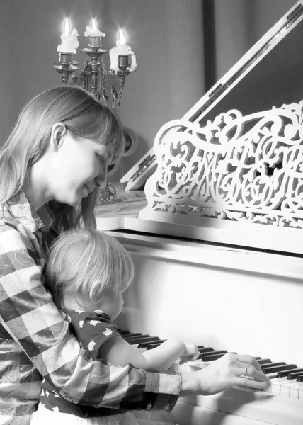 Мама с ребенком рядом с белым пианино — стоковое фото