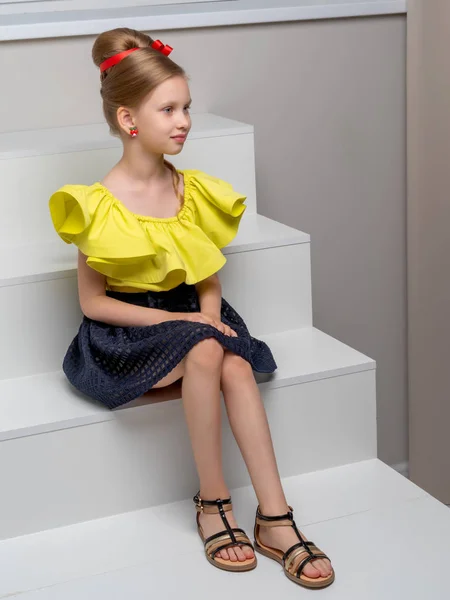 Beautiful little girl is sitting on the white staircase. — Stock Photo, Image