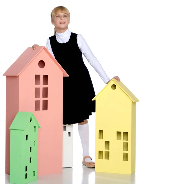 Little girl is playing with wooden houses. — Stock Photo, Image