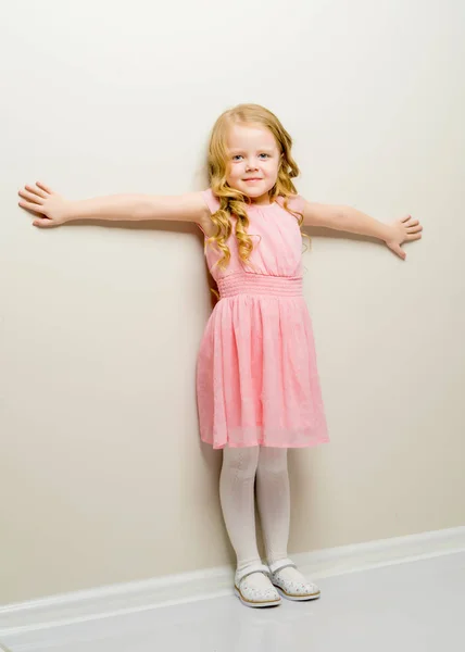 Een lief klein meisje leunde tegen de muur.. — Stockfoto