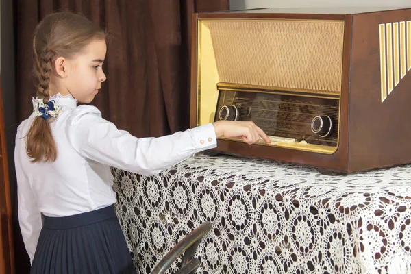 Little girl listens to old radio.