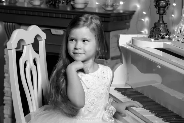 Klein meisje speelt piano bij kaarslicht. — Stockfoto