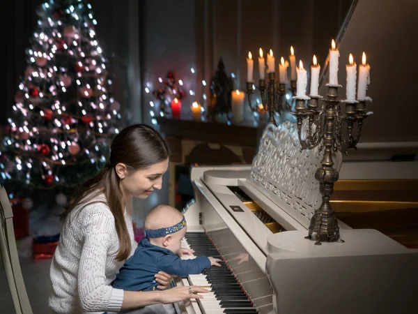 Μητέρα με ένα παιδί κοντά σε ένα λευκό πιάνο — Φωτογραφία Αρχείου