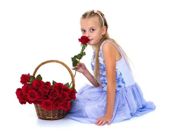 Schattig klein meisje met een mandje met bloemen. — Stockfoto