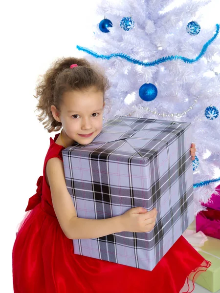 Kleines Mädchen mit einem Geschenk am Weihnachtsbaum. — Stockfoto