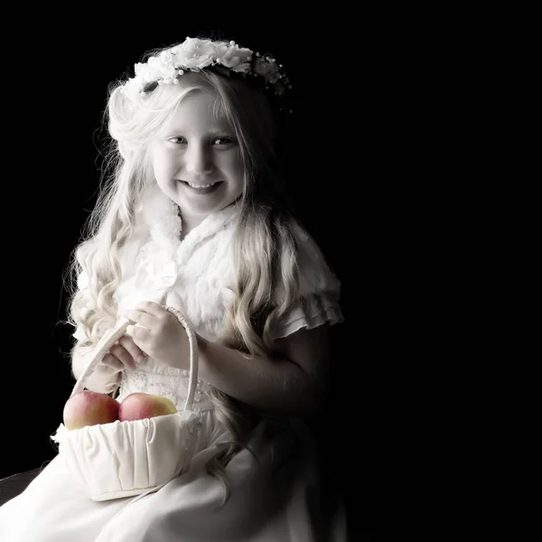 Klein meisje met een mand van appels. — Stockfoto