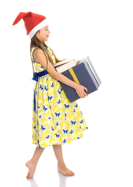 Ein kleines Mädchen mit einem Geschenk im Weihnachtsmann-Hut. — Stockfoto