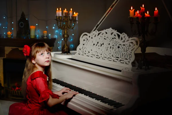 어린 소녀는 촛불을 켜고 피아노를 연주 한다. — 스톡 사진