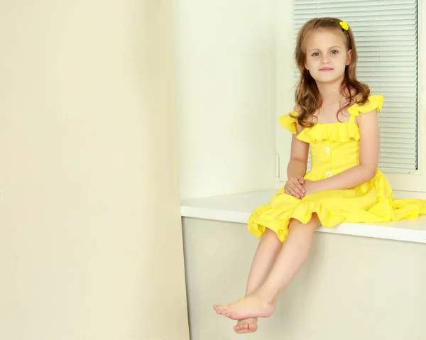Uma menina está sentada junto à janela com a Jalousie — Fotografia de Stock