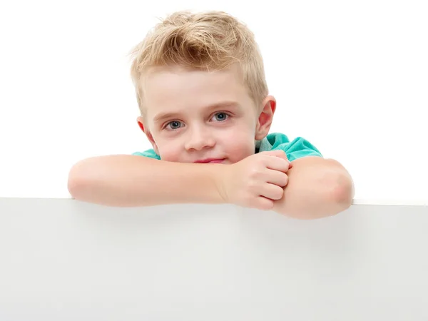 Een kleine jongen is op zoek achter een lege banner. — Stockfoto