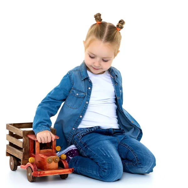 Little girl is playing with a wooden car. — Stock Photo, Image