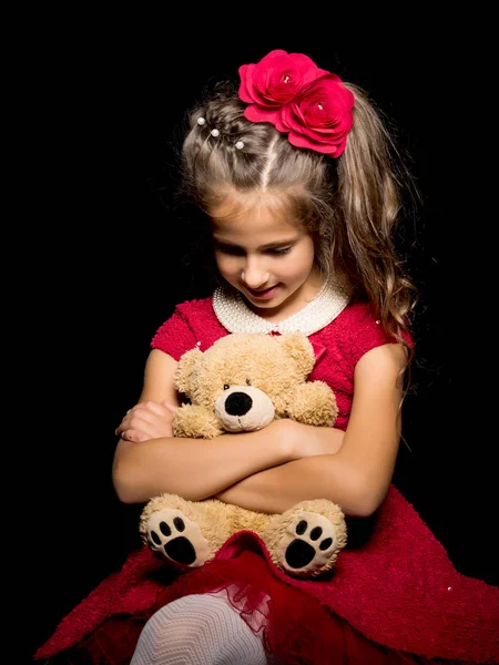 Menina com um ursinho de pelúcia em um fundo preto. — Fotografia de Stock