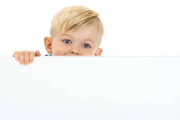 Un niño pequeño está mirando detrás de una pancarta vacía . — Foto de Stock