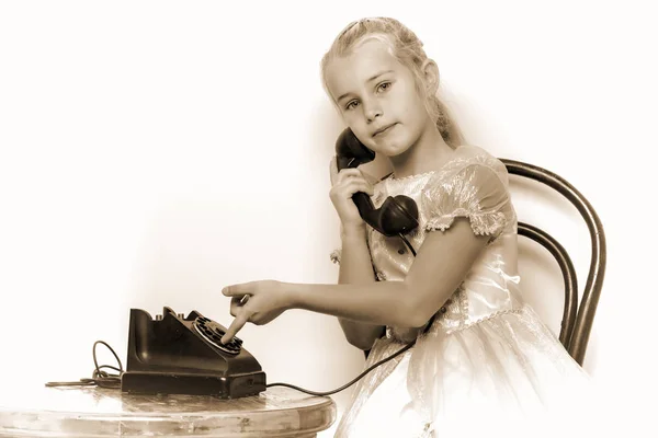 Una niña está sonando en el viejo teléfono. — Foto de Stock