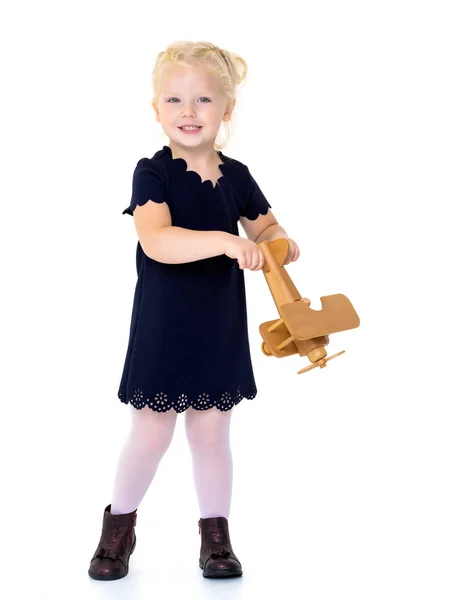 Niña está jugando con un avión de madera. — Foto de Stock