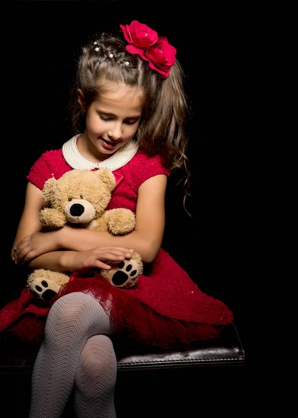 Siyah arka planda oyuncak ayısı olan küçük bir kız.. — Stok fotoğraf
