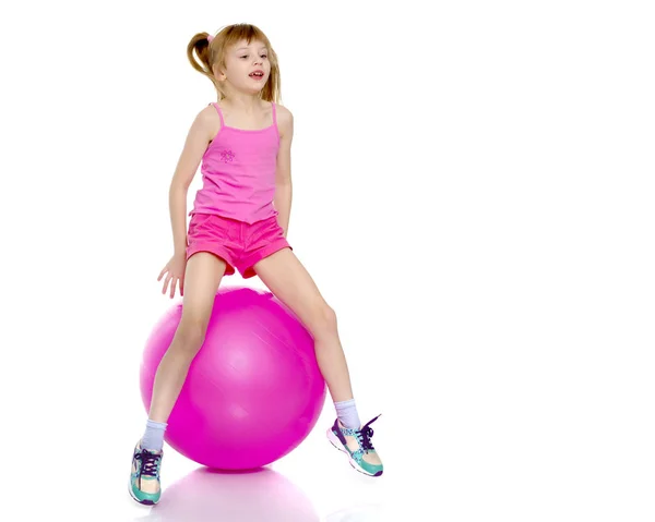 Uma menina está pulando na grande bola de ginástica . — Fotografia de Stock