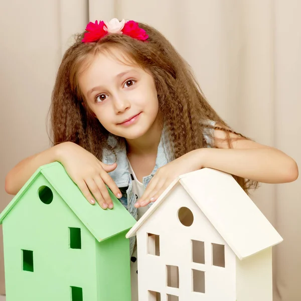 Ein kleines Mädchen blickt hinter einem Holzhaus hervor. — Stockfoto