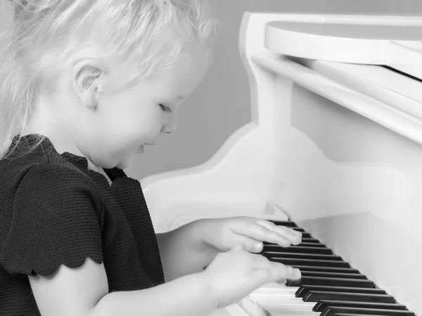 Kleines Mädchen spielt Klavier, Schwarz-Weiß-Foto. — Stockfoto