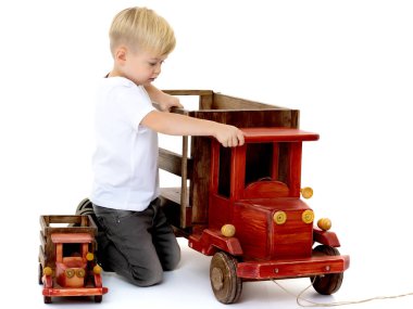 Küçük çocuk bir ahşap araba ile oynuyor.