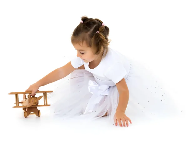 Kleines Mädchen spielt mit einem Holzflugzeug. — Stockfoto