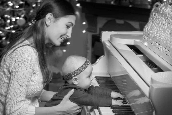 Bir çocuğun yanında beyaz piyano ile anne — Stok fotoğraf