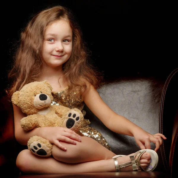 Menina com um ursinho de pelúcia em um fundo preto. — Fotografia de Stock