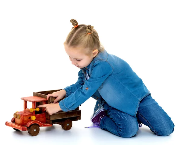 Kleines Mädchen spielt mit einem Holzauto. — Stockfoto