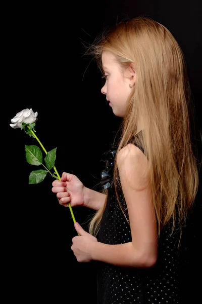 Bambina con un fiore bianco su sfondo nero . — Foto Stock