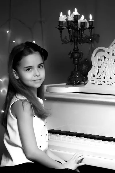 Menina toca piano à luz das velas. — Fotografia de Stock