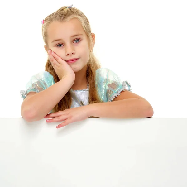 Een klein meisje kijkt van achter een leeg spandoek. — Stockfoto