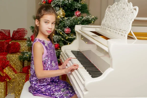 Liten flicka nära piano och julgran. — Stockfoto
