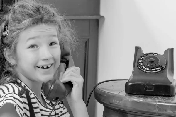 Une petite fille sonne sur le vieux téléphone. — Photo