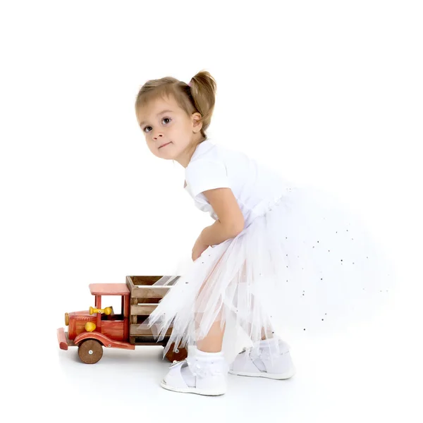 Kleines Mädchen spielt mit einem Holzauto. — Stockfoto