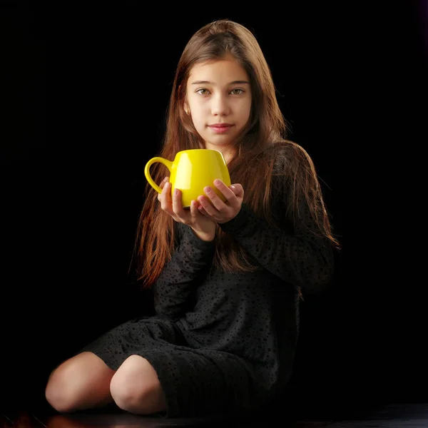 Маленька дівчинка з чашкою на чорному тлі . — стокове фото