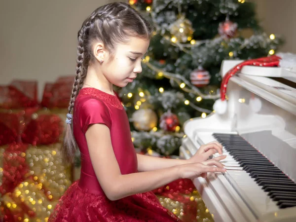 Niña cerca del piano y el árbol de Navidad . —  Fotos de Stock