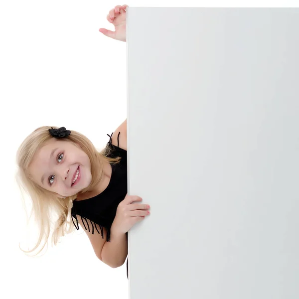 Uma menina está olhando por trás de uma bandeira vazia. — Fotografia de Stock