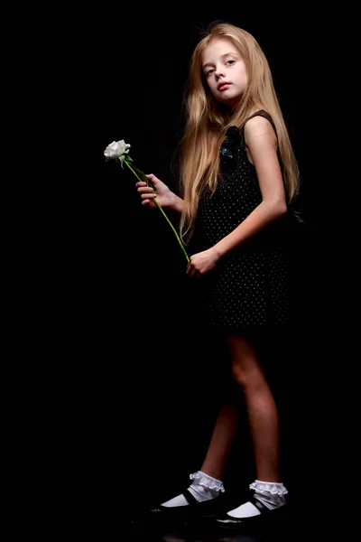 Маленька дівчинка з білою квіткою на чорному тлі . — стокове фото